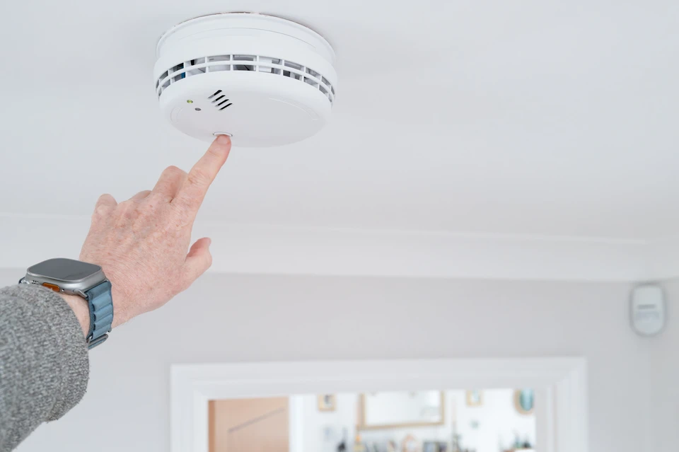 Homme installant un système de sécurité mural intérieur, programmant un boîtier de contrôle d'accès électronique avec clavier numérique et écran LCD