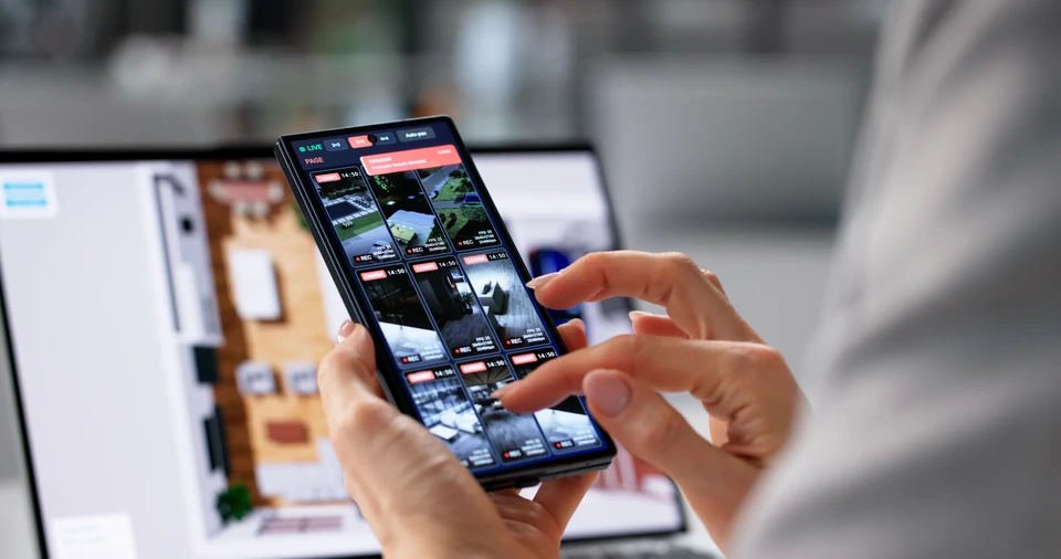 Intérieur moderne avec femme utilisant smartphone pour contrôler système de vidéosurveillance