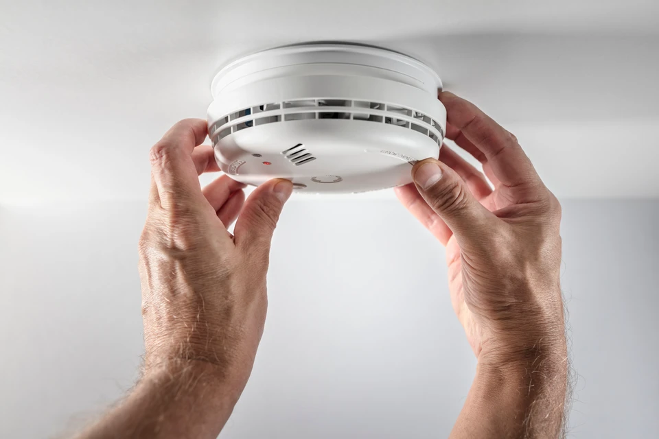 Gros plan sur les mains d'un technicien professionnel en tenue de travail qui installe ou configure un panneau de contrôle d'accès mural intégré à une porte sécurisée. Le technicien procède à des ajustements précis, montrant l'aspect sur mesure et personnalisé de l'installation. L'environnement est professionnel (intérieur de bâtiment commercial ou PME), avec un focus sur le détail technique et la rigueur de mise en œuvre. Lumière naturelle claire, profondeur de champ légèrement réduite pour mettre en avant le geste précis du professionnel.