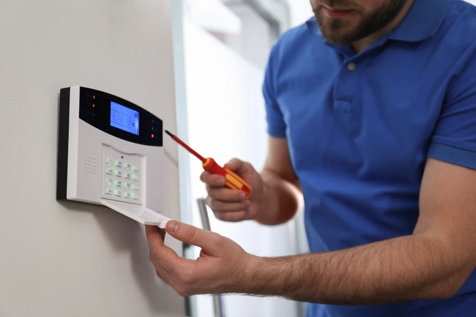 Installation de caméra de surveillance par un technicien professionnel sur plafond intérieur blanc
